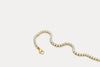 Gold tennis bracelet with clear rhinestone links and gold clasp, flat lay