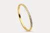 Gold slim bangle with continuous zirconia-style stones along the outer edge