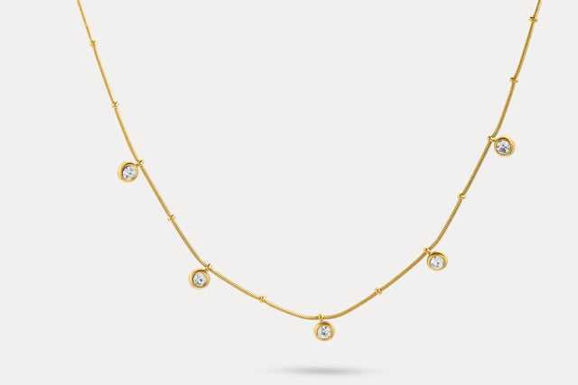 Gold charm necklace with evenly spaced round blue stone charms