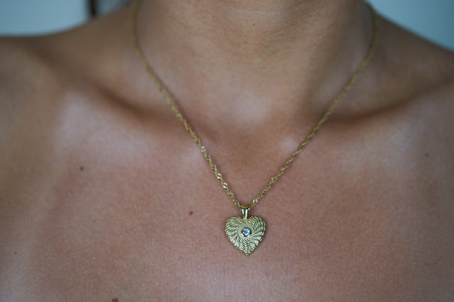 Gold heart pendant necklace with small blue gemstone