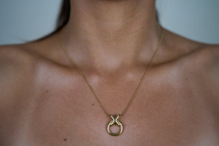 Circle pendant necklace with gold-tone round charm and linked X knot