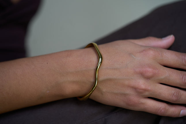 Gold wave cuff bracelet on wrist, smooth open bangle with curved ends