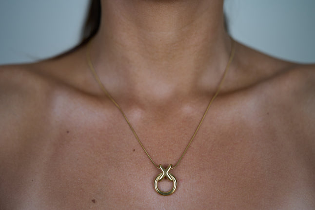 Circle pendant necklace with gold-tone round charm and linked X knot