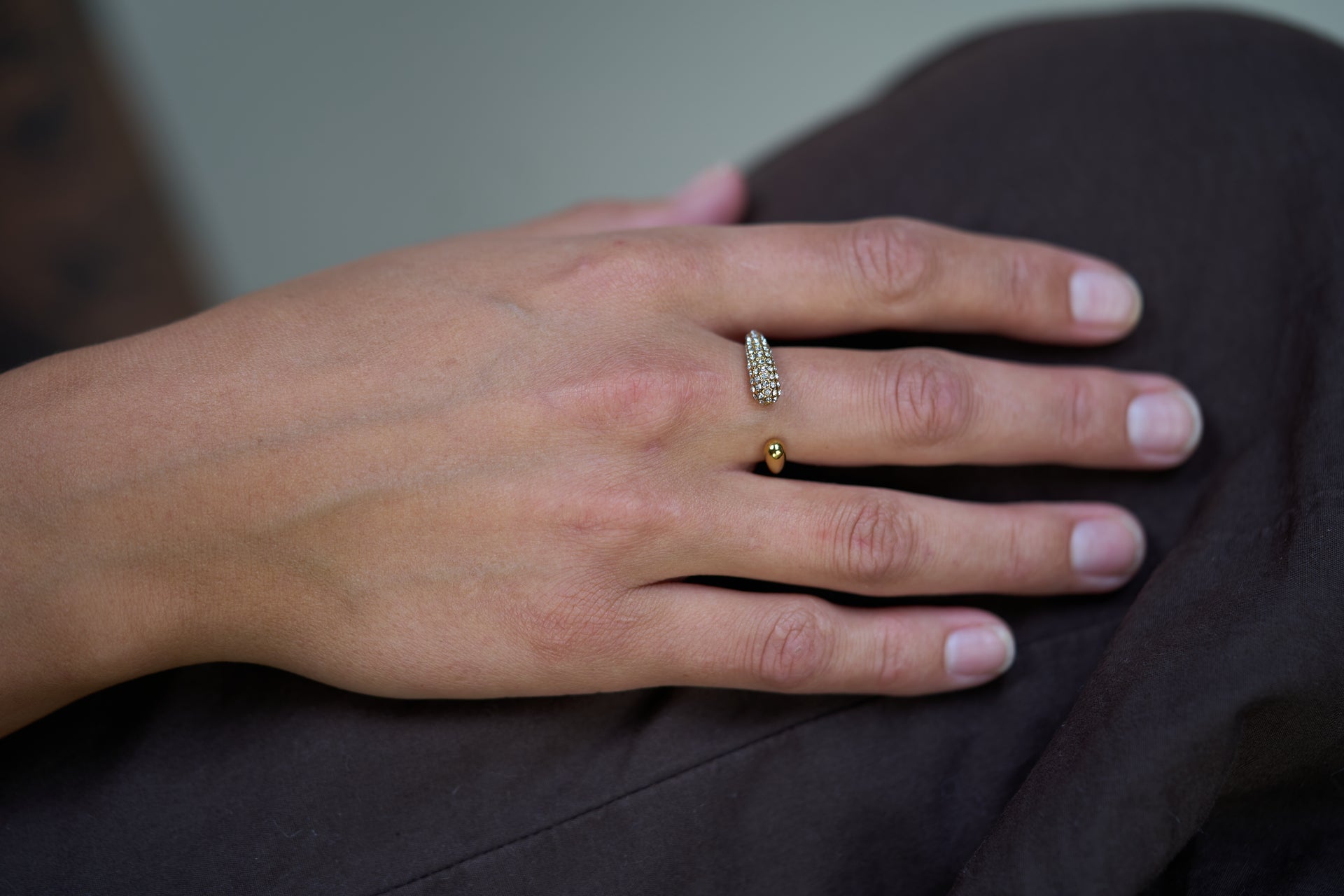 Gold crystal curve ring worn on finger, pavé stone detail