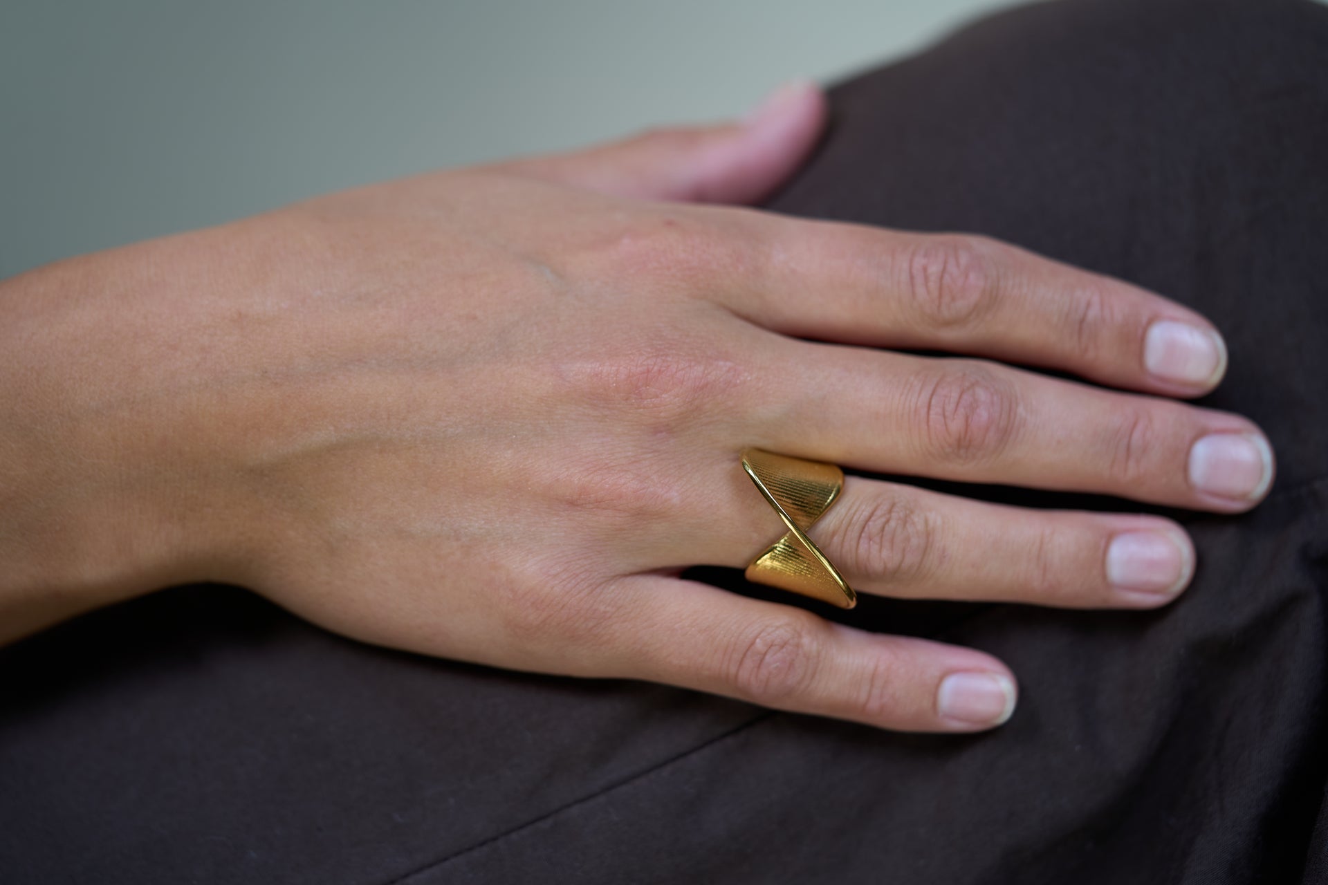 Shield-style ring on finger, gold tone, angled sculpted front