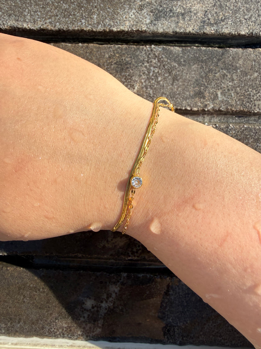 Gold double chain bracelet with small round blue-stone charm